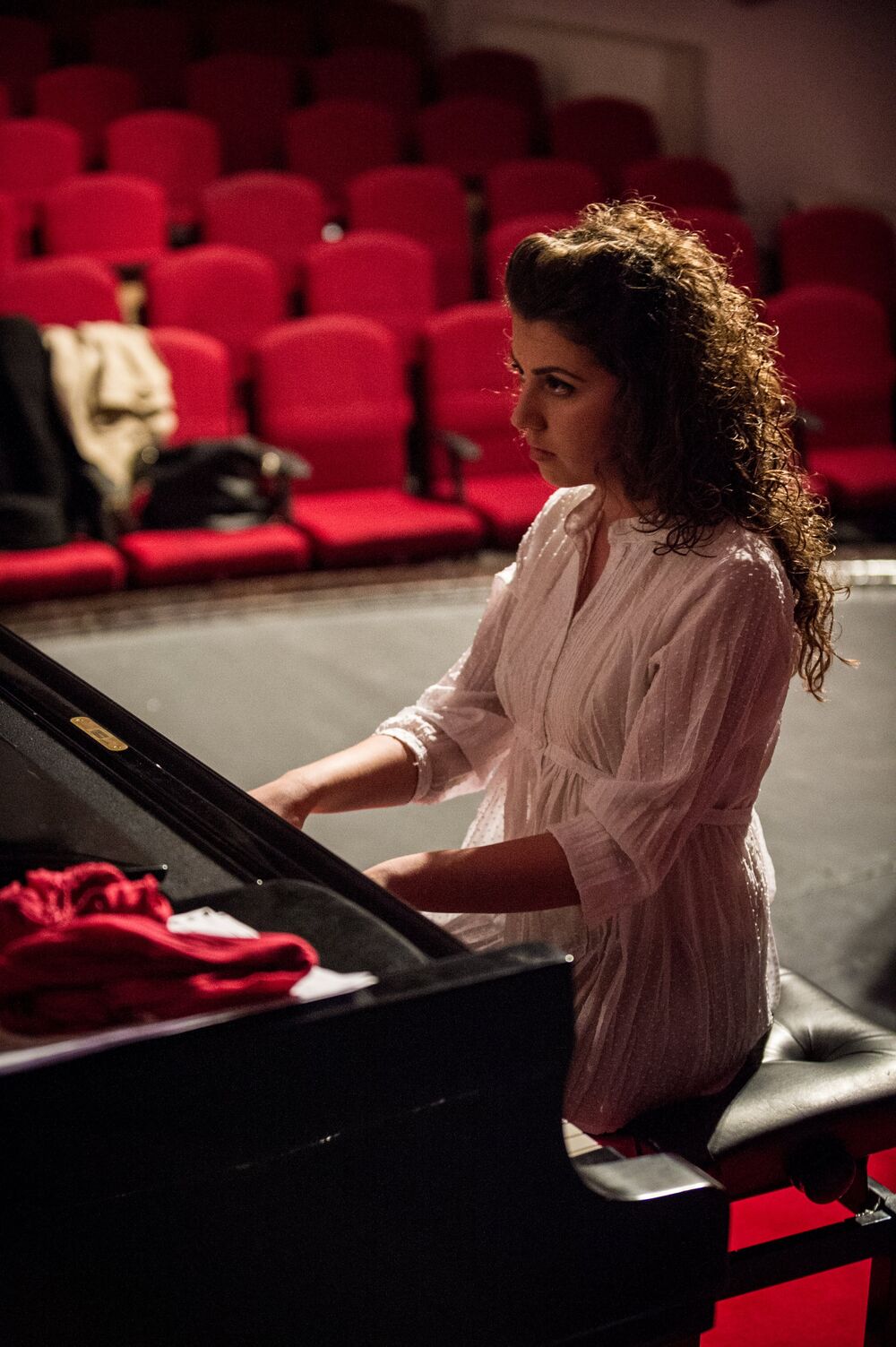 Playing at the piano in a theatre with red velvet seats