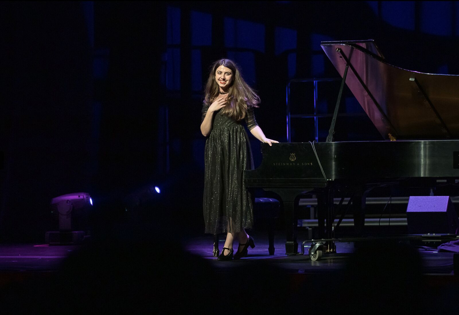 Smiling and bowing to the audience beside the piano